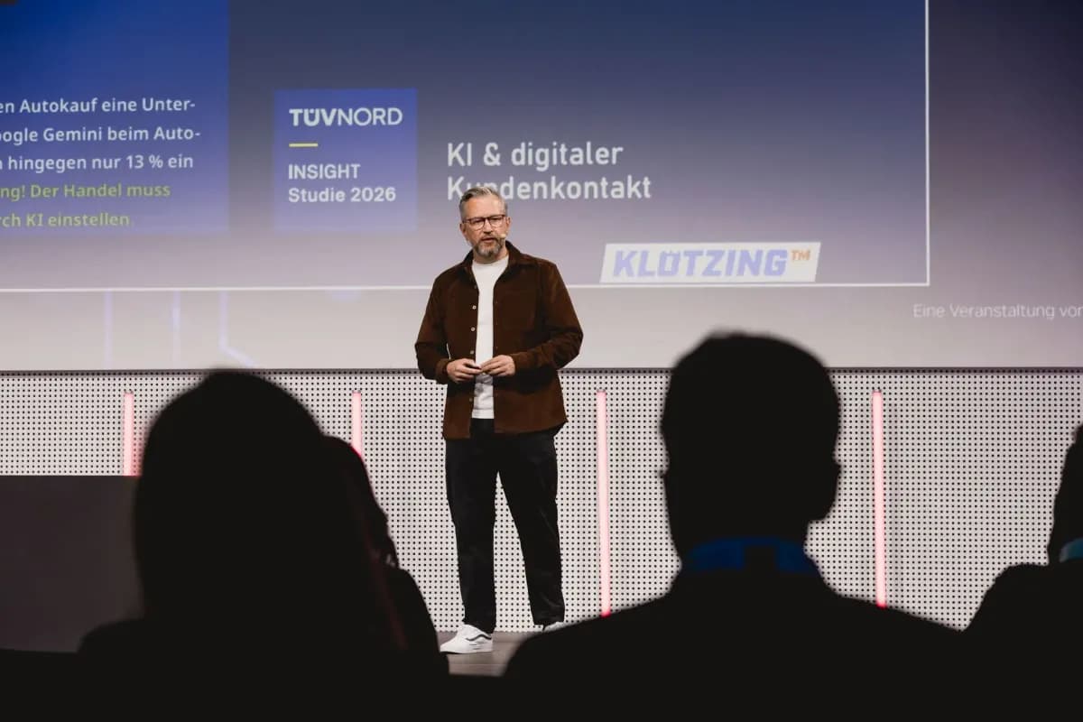 Tim Klötzing auf der Bühne des Automotive Business Day, hinter ihm eine Folie zu KI und digitalem Kundenkontakt