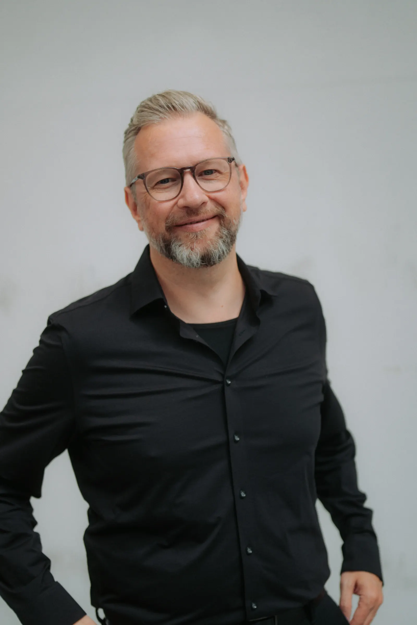 Tim Klötzing in schwarzem Hemd vor einer hellen Wand